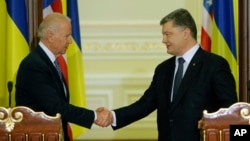 Wapres AS Joe Biden (kiri) dan Presiden Ukraina, Petro Poroshenko berjabat tangan usai konferensi pers bersama di Kyiv, Senin (7/12).