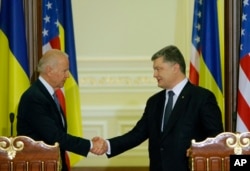 ຮອງ​ປະທານາທິບໍດີ ທ່ານ Joe Biden (ຊ້າຍ) ​ແລະ ທ່ານ Petro Poroshenko ປ. ຢູ​ເຄຣນ ຈັບ​ມື​ກັນ ຫຼັງ​ຈາກ ກອງ​ປະຊຸມ​ຖະ​ແຫຼ​ງຂ່າວ Kyiv, ນະຄອນຫຼວງ​ຂອງ ຢູ​ເຄຣນ 7 ທັນວາ, 2015.