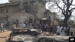Onlookers gather around a destroyed car at the site of a bomb blast at St. Theresa Catholic Church in Madalla, Nigeria, Sunday, Dec. 25, 2011.