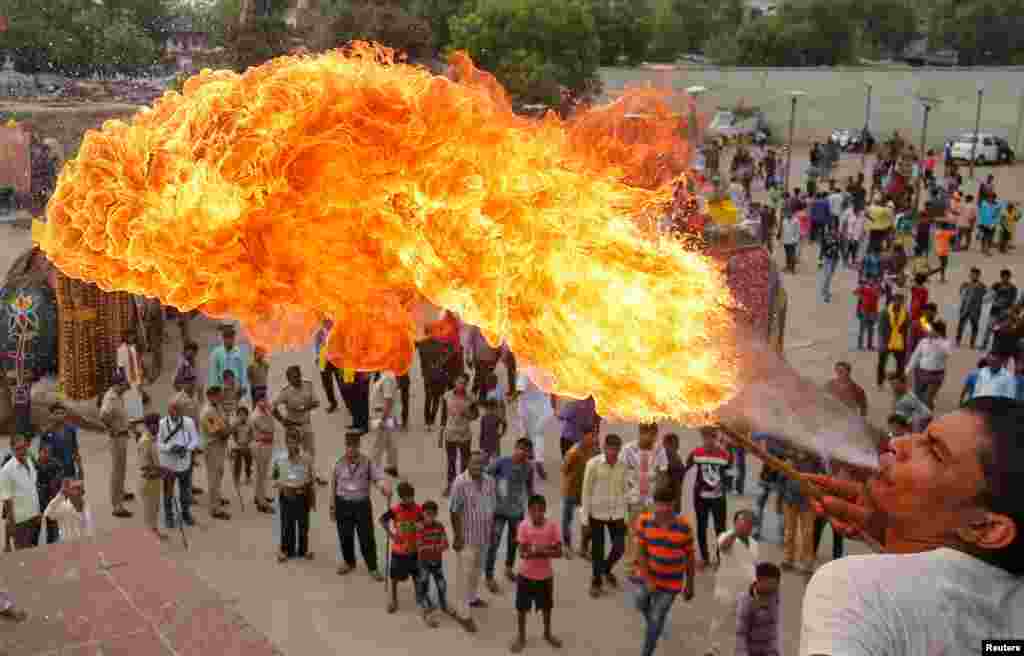 Seorang umat Hindu menunjukkan kebolehannya dalam beratraksi dengan api di prosesi Jal Yatra yang mendahului acara tahunan Rath Yatra, atau prosesi kereta perang, yang akan dilaksanakan pada tanggal 25 Juni di Ahmedabad, India.