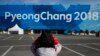 A volunteer takes pictures of a large banner at the Olympic Park ahead of the 2018 Winter Olympics in Gangneung, South Korea, Feb. 7, 2018.