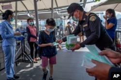 戴着防护口罩的泰国卫生官员在曼谷的一个商场里发放口罩。（2020年1月28日）