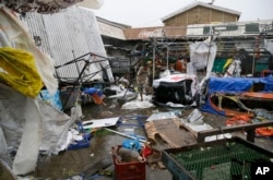 Residents walk along destroyed stalls at a public market from the strong winds of Typhoon Mangkhut in Tuguegrao city in Cagayan province, northeastern Philippines, Sept. 15, 2018.