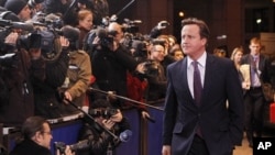 British Prime Minister David Cameron, center, speaks with the media as he arrives for an EU summit in Brussels, Dec. 8, 2011.