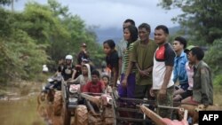 ຜູ້​ປະ​ສົບ​ໄພ​ນ້ຳ​ຖ້ວມ​ລໍ​ຖ້າ​ຮັບ​ການ​ຊ່ວຍ​ເຫຼືອ​ດ້ານ​ອາ​ຫານ​ໃນ​ເມືອງ ສະ​ໜາມ​ໄຊ, ແຂວງ​ອັດ​ຕະ​ປື, 27 ກໍ​ລະ​ກົດ 2018.