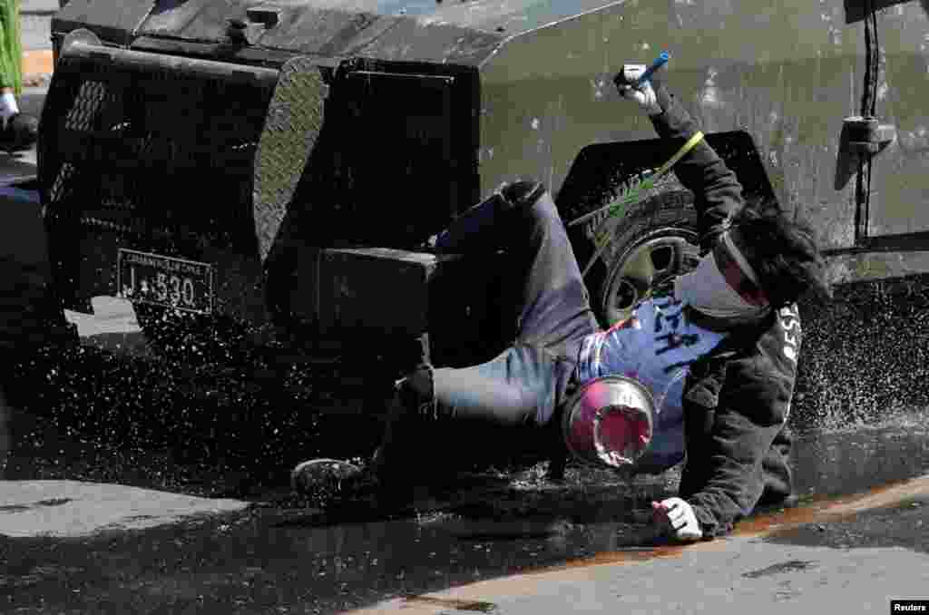 A demonstrator hangs from a riot police vehicle during a protest against Chile&#39;s state economic model in Santiago, Oct. 20, 2019.