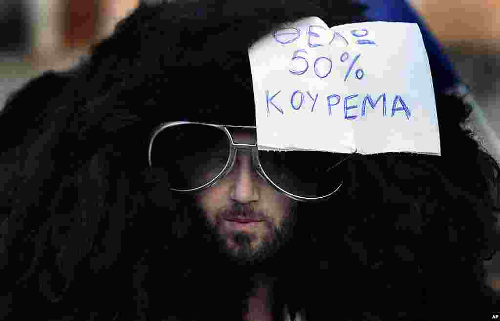 An anti-austerity protester wears a wig with a note that reads "I need a 50% hair cut" during a demonstration outside the Greek parliament in Athens' Syntagma Square on February 19, 2012. (Reuters)