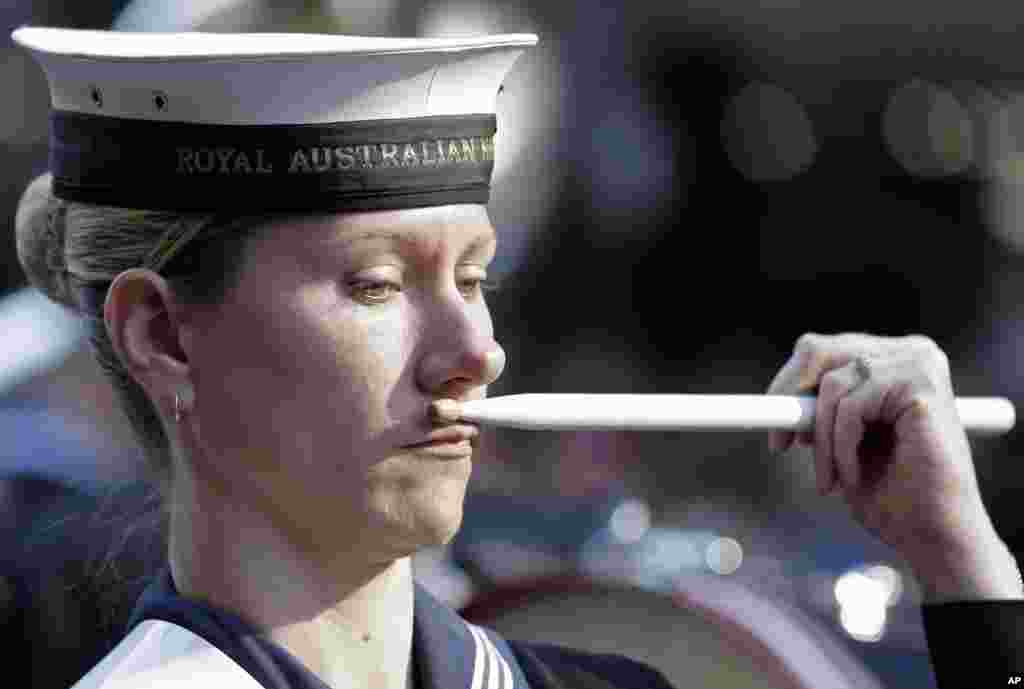 A drummer in the Royal Australian Navy Band raises a drumstick to her face as she marches in a parade commemorating ANZAC Day in Sydney, Australia. ANZAC Day is a day of remembrance in Australia and New Zealand that commemorates Australians and New Zealanders who served and died in all wars and conflicts.