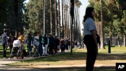FILE - People wait in line for a rapid antigen test at a COVID-19 testing site in Long Beach, Calif., Jan. 6, 2022. Millions of workers whose jobs don’t provide paid sick days are having to choose between their health and their paycheck.