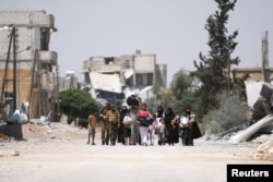 Syria Democratic Forces (SDF) fighters walk with people that fled their homes due to clashes between Islamic State fighters and Syria Democratic Forces (SDF) towards safer parts of Manbij, in Aleppo Governorate, Syria, August 7, 2016.