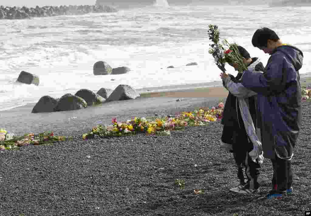 Taketo Endo, 12, right, and his brother Haruto, 10, offer prayers for their parents, who were killed in the March 11, 2011 earthquake and tsunami, at a seaside which was damaged by the disaster in Iwaki, Fukushima prefecture, March 11, 2012. (Reuters)