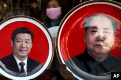 A woman looks at souvenir plates bearing images of Chinese President Xi Jinping, left, and late Chinese leader Mao Zedong on display for sale at a shop near Tiananmen Square in Beijing, Jan. 17, 2016.