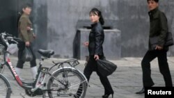 People walk past an electric bike in Pyongyang, North Korea, May 6, 2016.