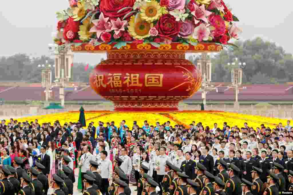 Participants stand in front of a giant flower basket arrangement set up ahead of the Chinese National Day, before a ceremony at the Monument to the People&#39;s Heroes on Tiananmen Square to mark Martyrs&#39; Day, in Beijing, China.