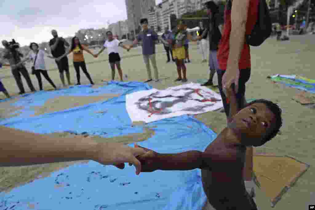 Mtoto aliyekuwa akicheza kwenye ufukwe wa Copacabana beach mjini Rio de Janeiro, Brazil, pamoja na familia yake waungana pamoja na watu wengine wanaoshikana mkono kuonesha umoja katika vita dhidi ya mabadiliko ya hali ya hewa&nbsp; duniani siku ya Jumatatu, Oct. 7, 2019.&nbsp; (AP)