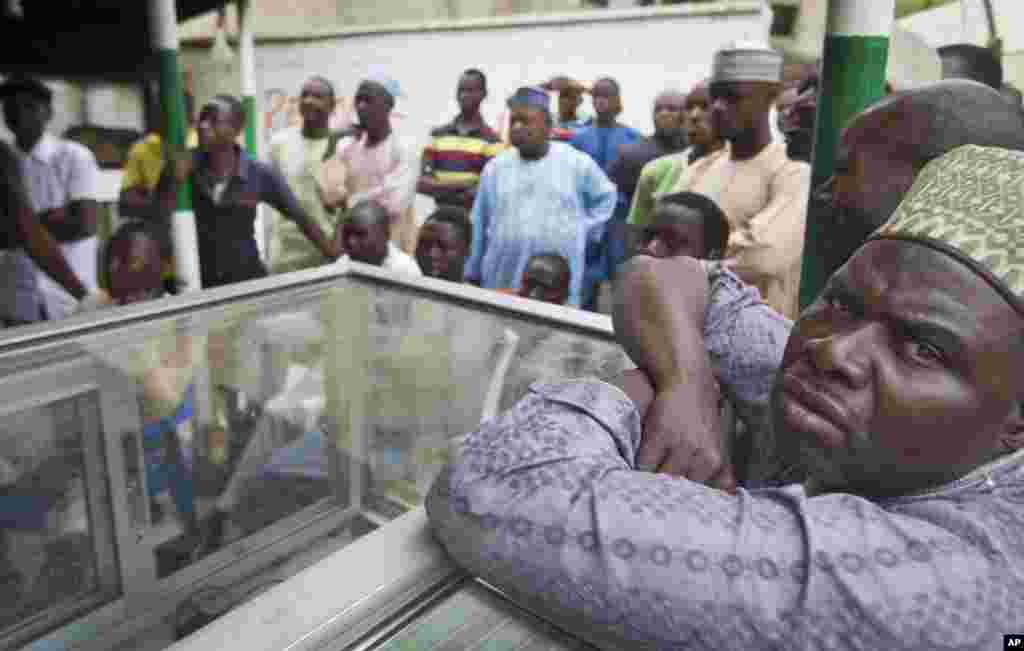 Pria-pria Nigeria menonton komisi pemilu mengumumkan hasil-hasil parsial di televisi di tempat penjagalan di Kano, Nigeria utara (31/3). (AP/Ben Curtis)