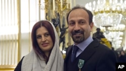 FILE - Iranian film director Asghar Farhadi and his wife, Parisa, pose after he was awarded the Officer of the Order of Arts and Letters medal, at the French Ministry of Culture, in Paris, France, Feb. 27, 2014.