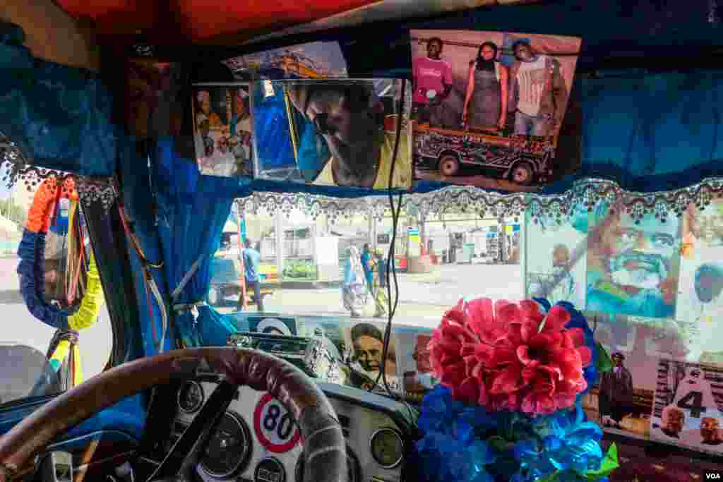 Driver Saliou appears in the mirror of his minibus. Its interior has typical decorations, such as pictures of Senegalese religious leaders and plastic flowers. (R. Shryock/VOA)