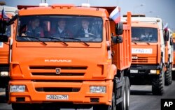 Russian President Vladimir Putin (C-R) drives a truck to officially open the much-anticipated bridge linking Russia and the Crimean peninsula, during the opening ceremony near in Kerch, Crimea, May 15, 2018.