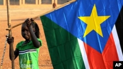 A girl holds a South Sudan flag on January 30 during the announcement of the preliminary results of voting on independence