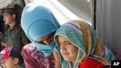 FILE - Syrian refugees wait outside a clinic at Zaatari Syrian refugee camp, in Mafraq, Jordan.
