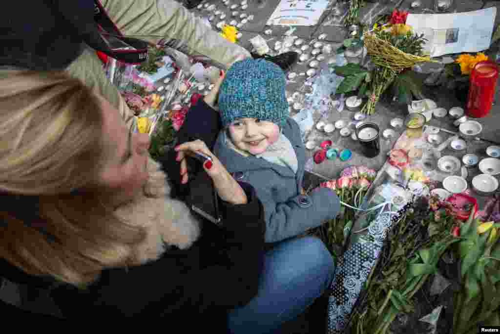 A woman looks at her daughter on the Place de la Bourse in central Brussels, on March 23, 2016 as people gather to observe a minute of silence in memory of the victims of the Brussels airport and metro bombings.