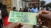 FILE- A man holds one of the new two-dollar banknotes issued by the Reserve Bank of Zimbabwe in Harare, Tuesday, Nov, 12, 2019. 