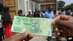 FILE: A man holds one of the new two-dollar banknotes issued by the Reserve Bank of Zimbabwe in Harare, Tuesday, Nov, 12, 2019.