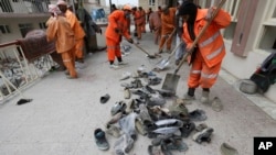 کارگران شهرداری کابل کفش های قربانیان حمله به مسجد باقر العلوم را جمع می کنند.