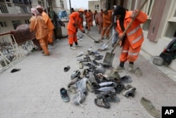 Afghan Municipality workers collect shoes of victims in front the Baqir-ul Ulom mosque after a suicide attack, in Kabul, Afghanistan, Nov. 21, 2016.