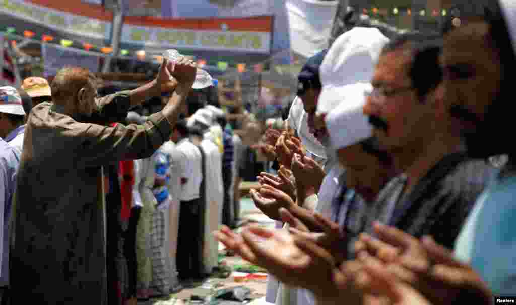 Un partidario de la Hermandad Musulmana y partidarios del depuesto ex presidente egipcio Mohamed Morsi ayuda a refrescar a sus correligionarios durante las oraciones del mediodía en la plaza Rabaa Adawiya de El Cairo, el lunes 15 de julio de 2013. 
