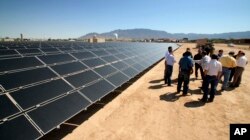 FILE - This April 20, 2011 file photo shows officials with Arizona-based First Solar and Public Service Co. of New Mexico gathering after the dedication of the utility's new 2-megawatt photovoltaic solar array in Albuquerque, N.M.