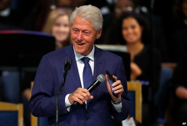 Former President Bill Clinton smiles as he plays a recording of Aretha Franklin on his phone during the funeral service for Franklin at Greater Grace Temple, Aug. 31, 2018, in Detroit.