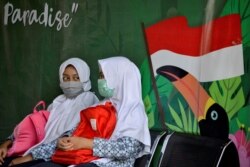 Dua pelajar berbincang sambil mengenakan masker di tengah pandemi virus corona di Banda Aceh, 10 Juni 2020. (Foto: AFP)