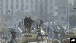 Supporters of President Hosni Mubarak, foreground , fight with anti-Mubarak protesters, rear, standing on army tanks in Cairo, February 2, 2011