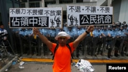 在香港政府机关门前，有防暴警察把守，示威者手持标语牌。（2014年9月27日）