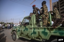 Members of the Sudanese military sit atop a pickup as protesters rally outside the army headquarters in the capital Khartoum, April 27, 2019.