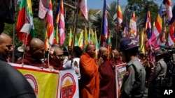 Polisi Myanmar menjaga ketat Kedutaan Thailand saat biksu dan warga Buddha melakukan aksi protes dengan memegang bendera agama dan Nasional di luar kantor tersebut, di Yangon, Myanmar, Jumat, 24 Februari, 2017. (AP Photo/Thein Zaw)