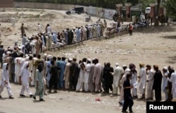 FILE - People, who fled the military offensive against Pakistani militants in North Waziristan, line up to receive food supply from the army in Bannu, in Pakistan's Khyber-Pakhtunkhwa province, June 25, 2014.