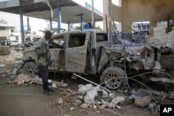 A Somali security man looks at the wreckage of a truck near the Nasahablood hotel in Mogadishu, Somalia, June 26, 2016. The Islamic extremist group al-Shabab claimed responsibility for the damage, inflicted in an attack the day before.