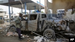 A Somali security man looks at the wreckage of a truck near the Nasahablood hotel in Mogadishu, Somalia, June 26, 2016. The Islamic extremist group al-Shabab claimed responsibility for the damage, inflicted in an attack the day before.