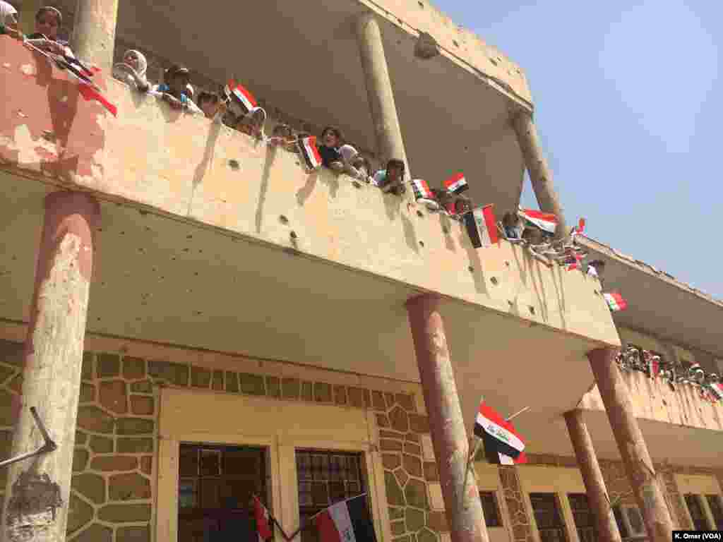 Para pelajar membagikan bendera Iraq di Sekolah Dasar Belqis (bagian kanan Mosul); sekolah ini rusak diterjang peluru, 18 Juli 2017.