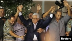Palestinian President Mahmoud Abbas (C) holds hands with Palestinian prisoners who were released from Israeli prisons during celebrations in the West Bank city of Ramallah, Aug. 14, 2013.