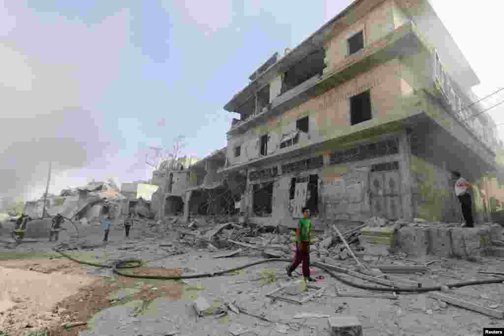 People inspect a site hit by what activists said was a barrel bomb dropped by forces loyal to Syria's President Bashar al-Assad in the al-Maadi neighborhood of Aleppo, June 20, 2014. 