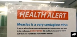 FILE - A notice for a health alert about measles is posted on the door of a medical facility in Seattle, Washington, Feb. 13, 2019.