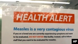 FILE - A notice for a health alert about measles is posted on the door of a medical facility in Seattle, Washington, Feb. 13, 2019.