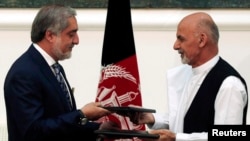 Kandidat-kandidat presiden Afghanistan Ashraf Ghani (kanan) dan Abdullah Abdullah menandatangani kesepakatan mengenai pembagian pemerintahan persatuan di Kabul (21/9). (Reuters/Omar Sobhani)