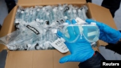Protective goggles are inspected after arriving at Bari airport in Italy on a plane that has travelled from Guangzhou, China, April 7, 2020. (REUTERS/Alessandro Garofalo)