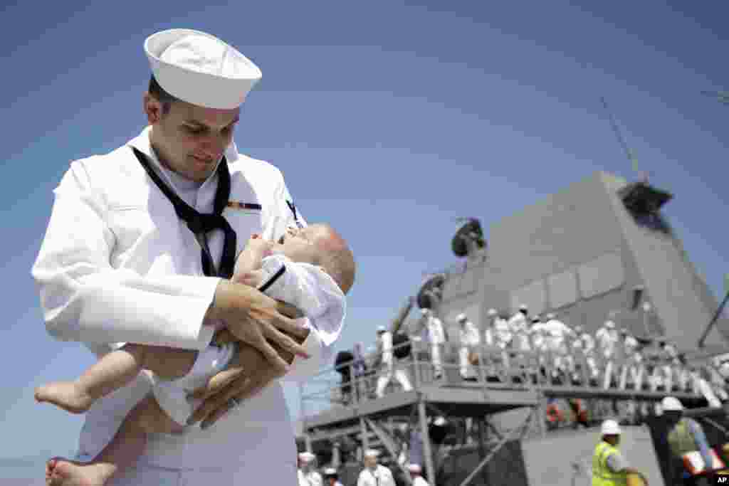 U.S. Naval Petty Officer Kyle Parrish holds his four-month-old son Benjamin, after arriving aboard the USS Dewey to the Naval base in San Diego, California, July 31, 2017.