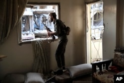 U.S.-backed Syrian Democratic Forces fighter looks through a window as he takes his position inside a destroyed apartment on the front line, in Raqqa, northeast Syria, July 27, 2017.